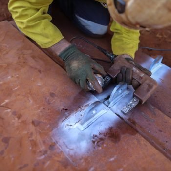 Top picture of NDT technician wearing safety glove spraying blac